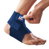 Blue ankle support brace being worn on a foot with a visible brand label.
