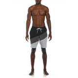 Man wearing black, gray, and white swim shorts on a white background