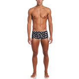 Man wearing black swim trunks with white pattern on a white background