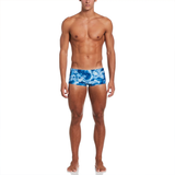 Man wearing blue tie-dye swim trunks on a white background