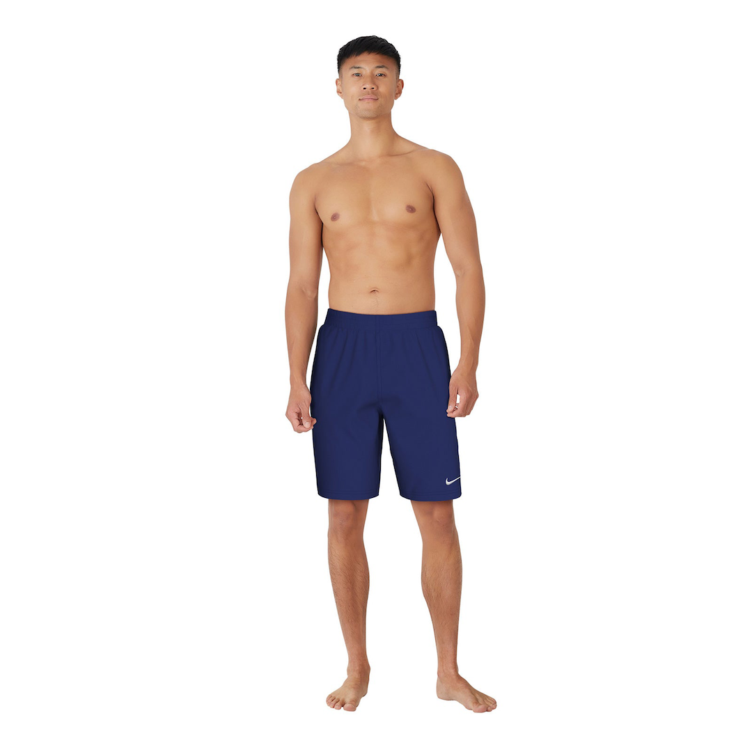 Man wearing navy blue swim shorts with a Nike logo on a white background